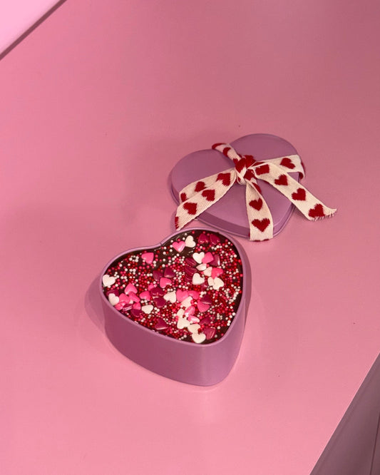 Heart-shaped box with pink and white confetti on a pink surface